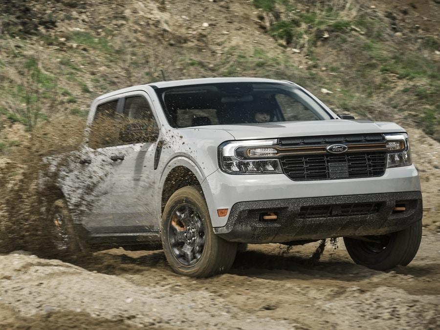 A 2024 Ford Maverick® in Oxford White is being driven off-road up a rocky hill
